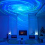 Projeção de galáxias e nebulosas no teto de uma sala escura, criando efeito de céu estrelado com cores azuis e verdes.