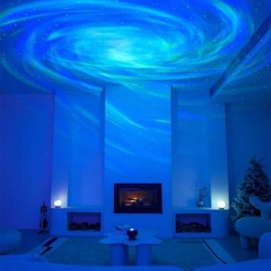 Projeção de galáxias e nebulosas no teto de uma sala escura, criando efeito de céu estrelado com cores azuis e verdes.