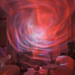 Projeção de galáxias e nebulosas em uma parede, com cores vermelhas, azuis e roxas, criando um efeito de espaço cósmico.