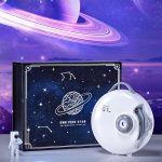 Projetor LED com tema de galáxia, caixa decorativa com ilustração de planeta e estrelas, incluindo um dispositivo branco com controle e um pequeno astronauta de brinquedo.