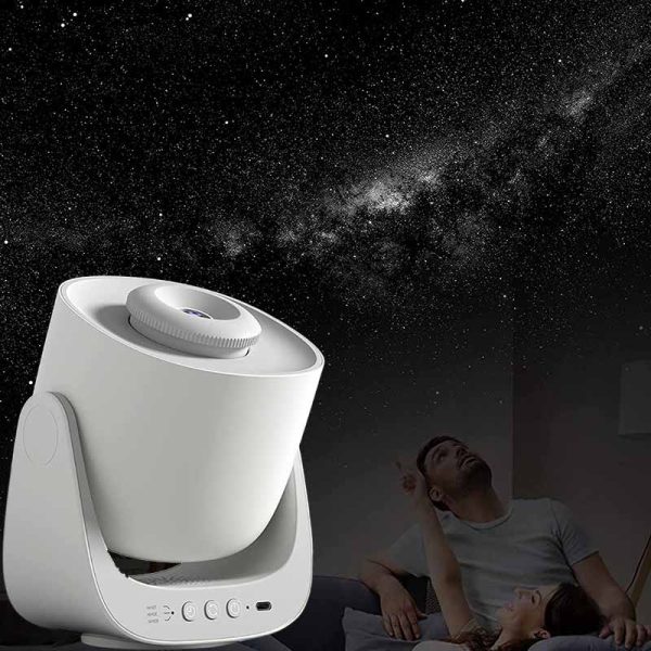 Projetor de estrelas branco a projetar o céu noturno na parede, com uma pessoa a observar e uma criança deitada na cama, ambiente escuro.