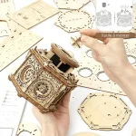 Peças de madeira cortadas com detalhes intricados para montar uma caixa de música 3D, com instruções visíveis ao fundo.