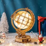 Globo terrestre em miniatura com iluminação, detalhes de mapas e estrutura de madeira, decorado com elementos natalícios como árvore de Natal e bonecos de neve.
