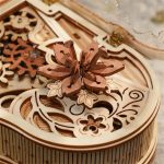 Peça de puzzle 3D com uma borboleta de madeira detalhada, parte de um conjunto de instrumentos musicais em madeira, vista de cima com detalhes das peças encaixadas.