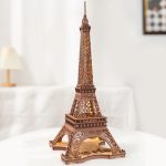 Miniatura da Torre Eiffel em peças de madeira, com iluminação interna, vista frontal detalhada.