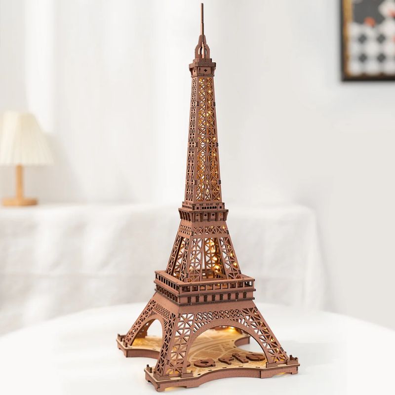 Miniatura da Torre Eiffel em peças de madeira, com iluminação interna, vista frontal detalhada.