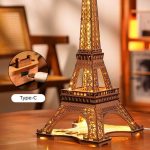 Modelo de torre Eiffel em madeira com iluminação LED, detalhes precisos, vista de diferentes ângulos, com controle de luz via Type-C.