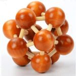 Estrutura de modelo de átomo com esferas de madeira laranja e varetas brancas, representando partículas subatómicas, vista frontal.