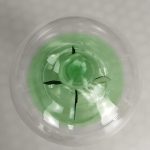 Radiómetro de Crookes com hélices pretas dentro de uma esfera de vidro transparente, iluminado por luz branca.