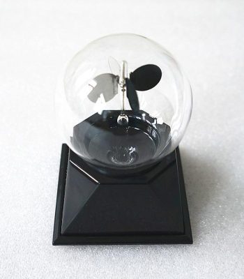 Radiómetro meteorológico com esfera de vidro transparente, hélice e base preta, usado para medir radiação solar e temperatura.