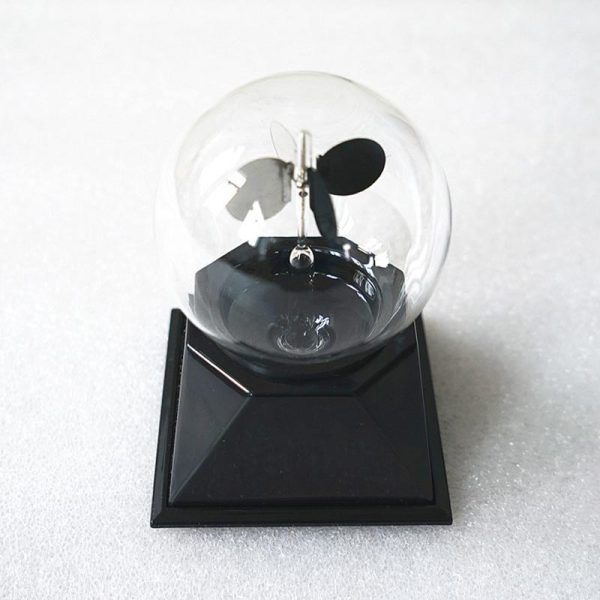 Radiómetro meteorológico com esfera de vidro transparente, hélice e base preta, usado para medir radiação solar e temperatura.