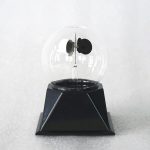 Radiómetro meteorológico com esfera de vidro transparente, hélice e base preta, usado para medir radiação solar e vento.