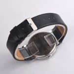 Relógio de pulso com pulseira de couro preta, mostrador prateado e caixa metálica, visto de trás.
