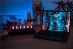 Conjunto de relógio Nixie com tubos de vidro iluminados, exibindo números vermelhos, ao lado de um portátil com tela de fundo artística, em ambiente com iluminação azul.