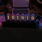 Conjunto de seis tubos Nixie exibindo números digitais, com luzes coloridas em fundo escuro, conectado a um computador portátil e equipamento de áudio.