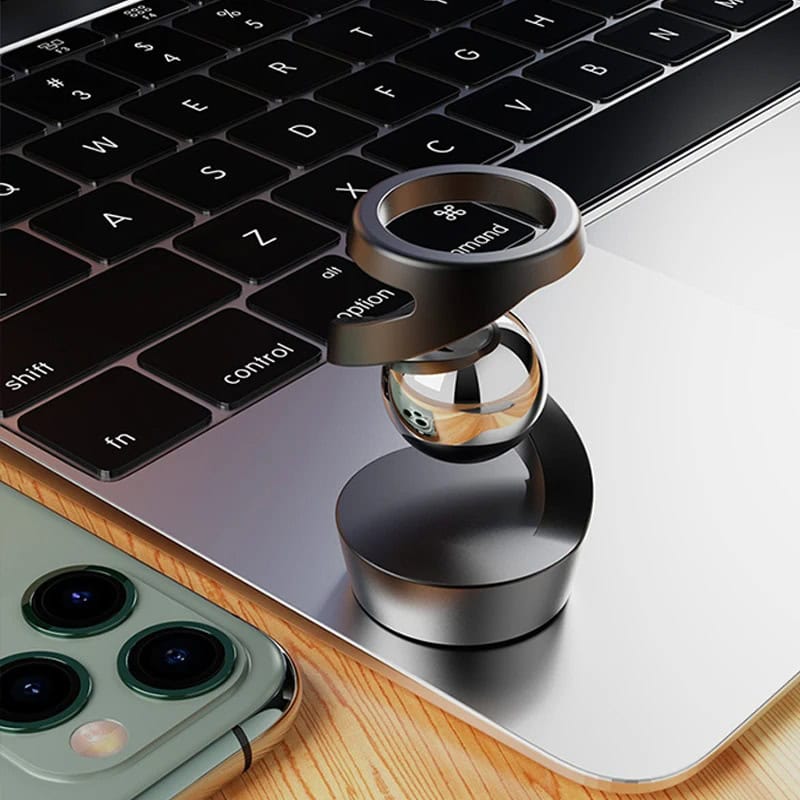Anel de metal com anel de vidro em portátil Anel de metal com anel de vidro colocado sobre o teclado de um portátil, com um smartphone ao lado.