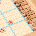Peças de madeira numeradas de 1 a 9, parte de um jogo de Sudoku, com uma peça de número 8 colocada na grelha.
