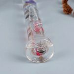Termómetro de vidro transparente com escala colorida e bolhas de ar visíveis, usado para medir temperaturas.