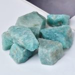 Vários pedaços de amazonite em bruto, com tonalidades azuis e verdes, com superfícies irregulares e textura natural.