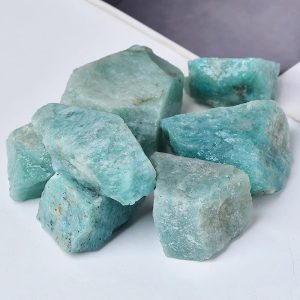 Vários pedaços de amazonite em bruto, com tonalidades azuis e verdes, com superfícies irregulares e textura natural.