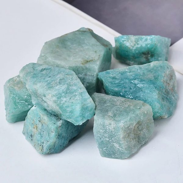 Vários pedaços de amazonite em bruto, com tonalidades azuis e verdes, com superfícies irregulares e textura natural.
