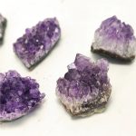 Quatro pedaços de ametista bruta com cristais roxos, diferentes ângulos e tamanhos, sobre fundo branco.