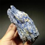 Cianite azul em bruto com estrutura cristalina visível, mostrando tonalidades de azul e detalhes de textura.