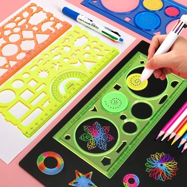 Espirógrafo clássico em plástico verde com desenhos coloridos feitos com caneta branca, rodeado por réguas, moldes e lápis de cores variadas.