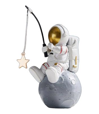 Estatueta de um astronauta sentado na lua, segurando uma vara de pescar com uma estrela de madeira na ponta, com capacete dourado e mochila espacial.