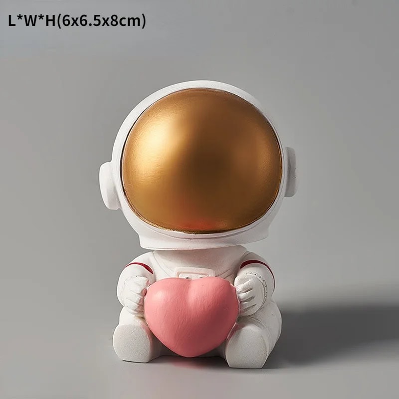 Estatueta de Astronauta com Coração Estatueta de astronauta com capacete dourado e corpo branco, segurando um coração rosa, em posição sentada.