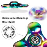 Fidget spinner de metal com acabamento iridescente, destaque para os rolamentos de aço inoxidável e o design de três braços.