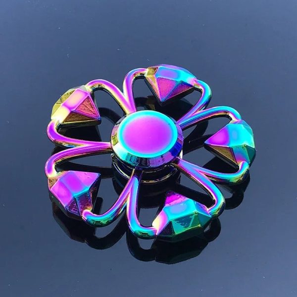 Fidget spinner com efeito holográfico, detalhes em forma de diamante, centro circular brilhante, sobre fundo escuro, destaque para as cores iridescentes.