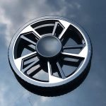 Roda de plástico preto e branco com design geométrico, vista superior, refletindo o céu nublado.