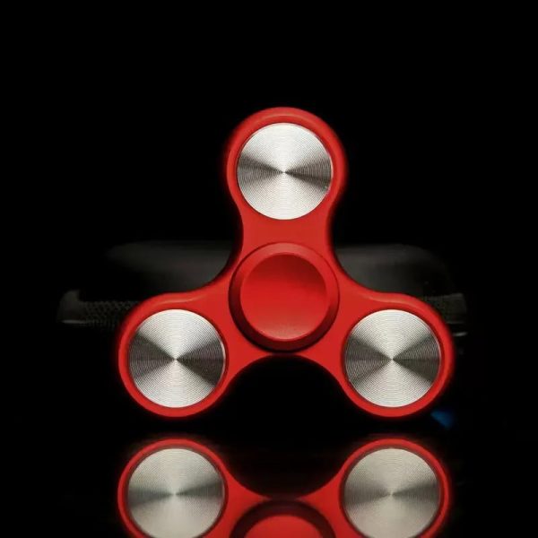 Fidget spinner vermelho com três braços, cada um com uma rotação metálica, sobre fundo preto.