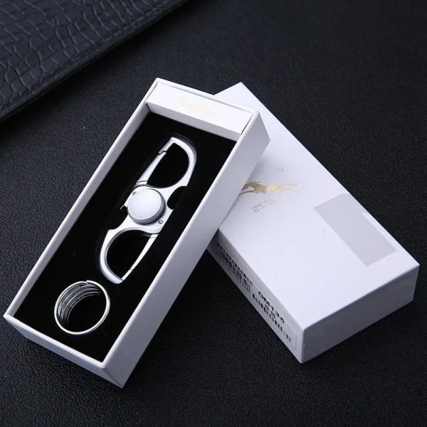 Fidget spinner porta-chaves branco com design moderno, colocado numa caixa de apresentação branca com detalhes dourados, sobre fundo preto.