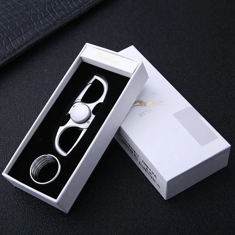 Fidget spinner porta-chaves branco com design moderno, colocado numa caixa de apresentação branca com detalhes dourados, sobre fundo preto.