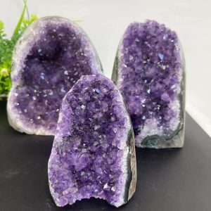 Três geodos de ametista com cristais roxos brilhantes, diferentes ângulos e detalhes de perto, sobre fundo neutro.