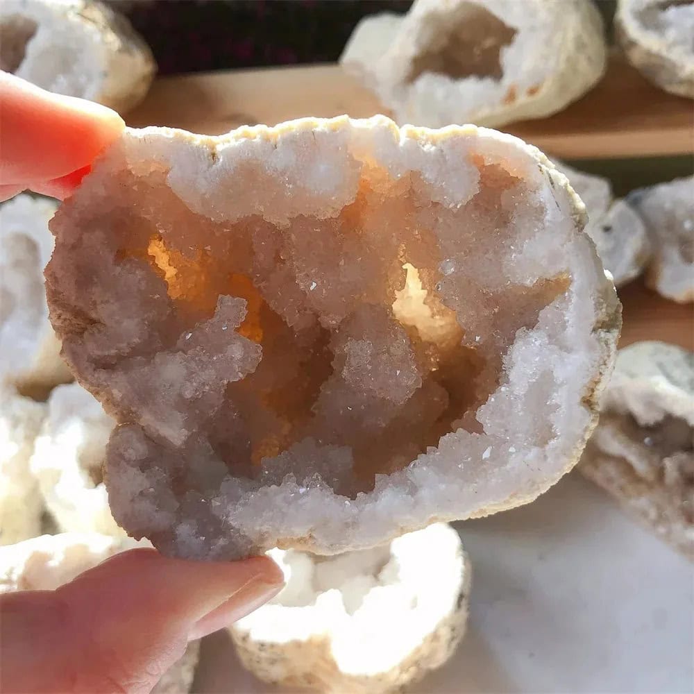 Geodo de cristal de rocha aberto, mostrando cristais dourados e brancos no interior, com textura irregular na superfície exterior.
