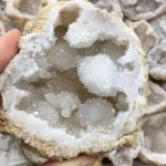 Geodo de cristal de rocha com cristais brancos e transparentes, interior oco com cristais brilhantes, superfície irregular e textura granulada.