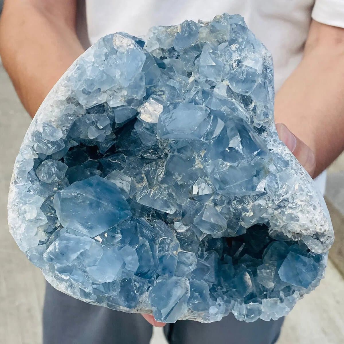 Geode de pedra celestina com cristais azuis transparentes e estrutura cristalina visível, vista de perto com detalhes de suas formações internas.