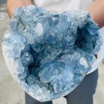 Geode de Pedra Celestina com cristais azuis brilhantes, vista de perto mostrando detalhes das formações cristalinas internas.