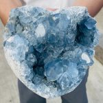 Geode de Pedra Celestina com cristais azuis brilhantes, vista de perto mostrando detalhes das formações cristalinas internas.