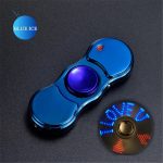 Fidget spinner com luz LED azul acesa, acompanhado de um disco com letras iluminadas em azul e vermelho, sobre fundo escuro.