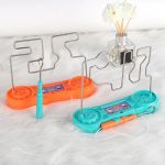 Jogo de destreza elétrico com fios de metal, base colorida em laranja e azul, e componentes de plástico, ideal para atividades educativas.