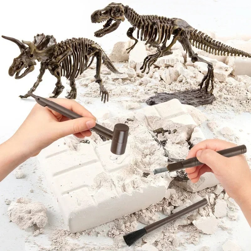 Jogo de Escavação de Dinossauros Duas mãos a usar ferramentas de escavação em uma caixa de areia com fósseis de dinossauros e esqueletos de dinossauros ao fundo.