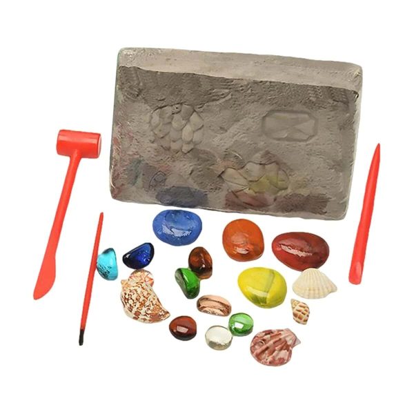 Bloco de areia com pegadas e ferramentas de escavação, várias pedras coloridas e conchas ao redor, usado para atividades de arqueologia educativa.