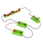 Conjunto de componentes de eletricidade infantil com fios, lâmpadas e baterias em base verde, usado para experimentos educativos de eletricidade.