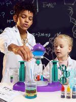 Duas crianças a realizar um experimento de laboratório com tubos de ensaio, reagentes coloridos e equipamento de química em sala de aula.