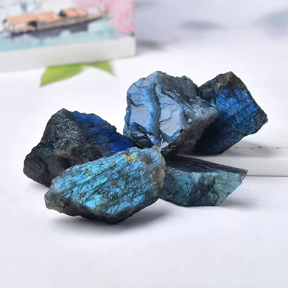 Conjunto de pedras de labradorite bruta com efeito iridescente azul e cinza, exibindo texturas naturais e brilho metálico.