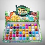 Conjunto de ovos de dinossauro coloridos com diferentes cores e padrões, exibidos numa caixa decorada com desenhos de dinossauros e vegetação.